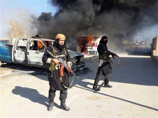 FILE - This undated file image posted on a militant website on Jan. 4, 2014, which is consistent with other AP reporting, shows Shakir Waheib, a senior member of the al-Qaida-linked Islamic State of Iraq and the Levant (ISIL), left, next to a burning police vehicle in Iraq's Anbar Province. The past year, ISIL _ has taken over swaths of territory in Syria, particularly in the east. It has increasingly clashed with other factions, particularly an umbrella group called the Islamic Front and with Jabhat al-Nusra, or the Nusra Front, the group that Ayman al-Zawahri declared last year to be al-Qaidas true representative in Syria. That fighting has accelerated the past month. (AP Photo via militant website, File)