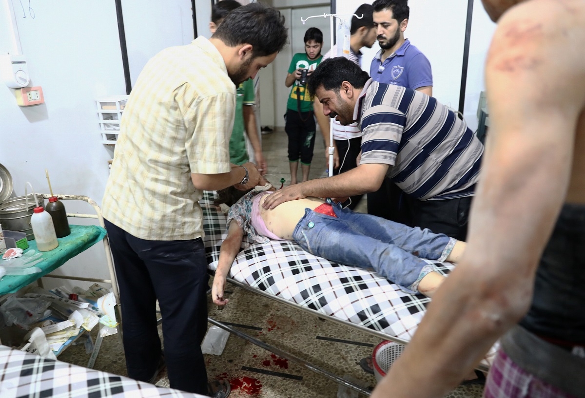A Syrian man stands next to his daughter as she receives treatment at a makeshift hospital following a reported air stike on the rebel-held town of Douma, east of the capital Damascus, on August 23, 2016.  
